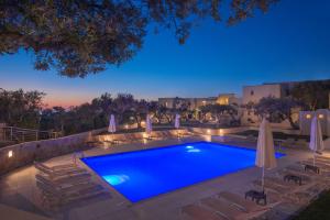 a swimming pool with chairs and umbrellas at night at Ourania Apartments Hotel in Gouves +33 photos
