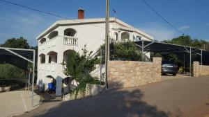 a white house with a fence in front of it at Apartmani Barbara in Vinjerac