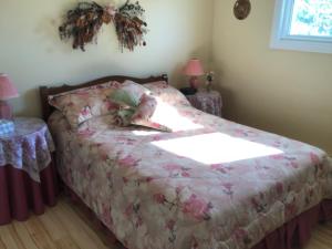 1 dormitorio con 1 cama con edredón rosa en Gîte Au Bord de la Baie, en Bouctouche