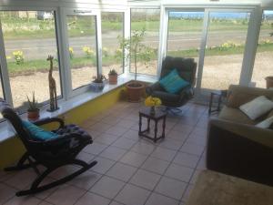 a living room with two chairs and a couch and windows at Creag Na Mara B&B in Thurso