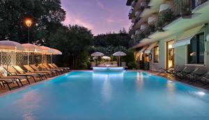 a large swimming pool with chairs and a building at Palace Hotel San Pietro in Bardolino