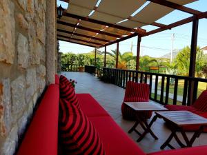 un patio con sillas y mesas rojas y una pared de piedra. en Villa Kizlan Ova, en Datça