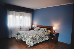 a bedroom with a bed with a blue wall and two lamps at Hotel Brisas del Sella in Ribadesella