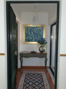 a hallway with a table and a painting on the wall at Cantinho do Céu in Vila Real de Santo António