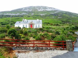 a white house with a red door on a hill at Dunlewey Lodge - Dunlewey, Gweedore in Gweedore