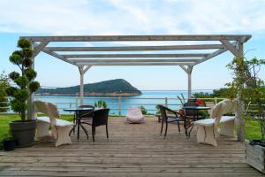 a wooden deck with chairs and a table with a view of the ocean at Agorastos Hotel in Koinyra