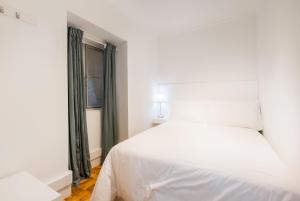een wit bed in een kamer met een raam bij Your Place in Lisbon in Lissabon