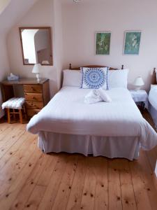 - une chambre avec un grand lit blanc et du parquet dans l'établissement Dunlewey Lodge - Self Catering Donegal, à Gweedore