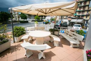 un tavolo con sedie e un ombrellone su un patio di La Caravella a Loano