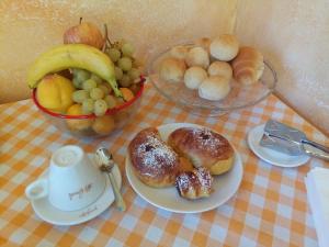 un tavolo con un piatto di prodotti da forno e un cesto di frutta di B&B Ca dei Fre a Genova