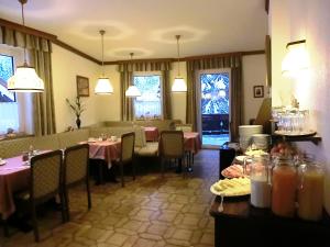 a dining room with tables and chairs and windows at Hotel garni Landhaus Bürtlmair in Hinterstoder