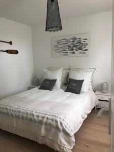 um quarto com uma cama branca e 2 almofadas em La ravissante ferretcapienne em Lège-Cap-Ferret