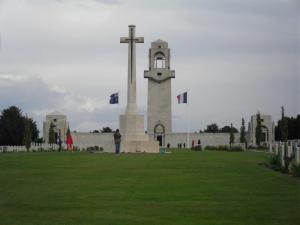 um homem parado em frente a uma igreja com uma cruz em Le gite de Beatrice et Laurent em Villers-Bretonneux