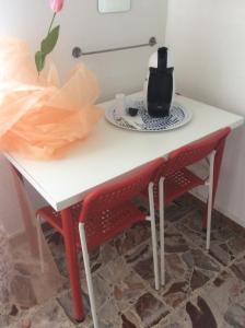 einem weißen Tisch mit zwei roten Stühlen und einer Teekanne darauf in der Unterkunft Casa Giulia In in Pisa