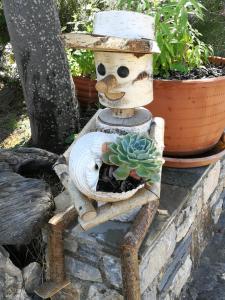 a wooden scarecrow sitting on a chair with a potted plant at Christou Homes in Steni Vala Alonissos