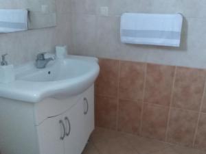 La salle de bains est pourvue d'un lavabo blanc et d'un miroir. dans l'établissement Apartman Mara, à Šestanovac