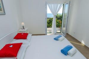a bedroom with a white bed with red and blue pillows at Apartment Veve in Privlaka