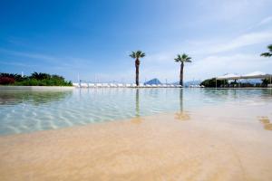 una piscina d'acqua con palme su una spiaggia di La Tonnara di Bonagia Resort a Valderice