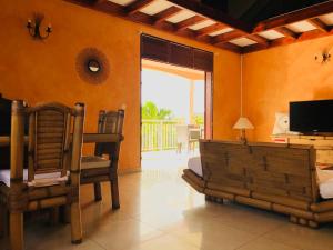 a living room with orange walls and a television and chairs at Villa Le sucrier in Terre-de-Haut