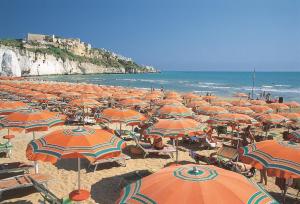 un grande gruppo di ombrelloni arancioni su una spiaggia di Hotel Degli Aranci a Vieste