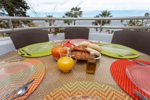 een tafel met een bord eten en sinaasappelsap bij Villa Venecia, Apartamento de Lujo en 1º línea de playa + parking in Málaga