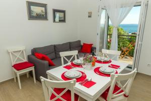 a white dining room with a table and a couch at Apartment Veve in Privlaka