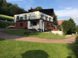 a house with a balcony on top of a yard at Na Markówce in Brenna