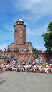 a group of people sitting on a wall in front of a lighthouse at APARTAMENT SŁONECZNY in Kołobrzeg
