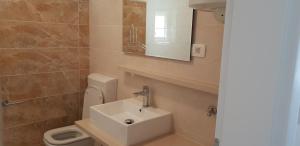 un bagno con lavandino, WC e specchio di Apartments Mia Bilo a Podgreben Altre 57 foto