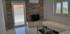 - un salon avec un canapé et une télévision dans l'établissement Apartments Mia Bilo, à Podgreben