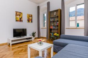 a living room with a blue couch and a tv at Old Town Clock Tower Apartment in Kotor