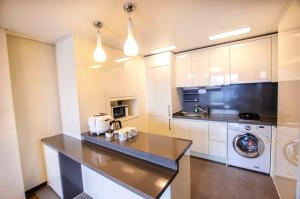 uma cozinha com armários brancos e uma máquina de lavar e secar roupa em Plea De Blanc Hotel & Residence em Busan