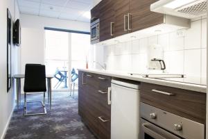 an office kitchen with wooden cabinets and a table at ApartHotel Faber in Aarhus