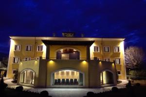 a large yellow building with lights on it at night at La Dimora del Baco Hotel in LʼAquila