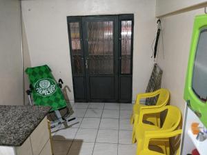 uma cozinha com cadeiras amarelas e uma porta preta em Casa em Fortaleza