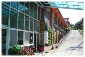 a building with windows and a sidewalk next to a street at Wan Jin Hot Spring in Wanli District