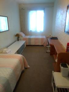 a hotel room with two beds and a desk and a window at Te Aputa Lodge formerly La Casa Te Puru Lodge in Te Puru +18 photos