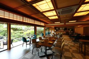 ein Esszimmer mit Tischen, Stühlen und Fenstern in der Unterkunft Nanzenji sando KIKUSUI in Kyoto