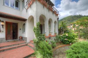 a house with a red door and some bushes at Appartamento in Villa a 5 KM dal mare in Albisola Superiore