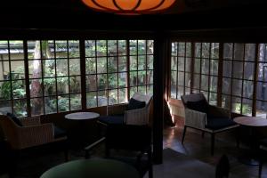a room with chairs and tables and windows at Nanzenji sando KIKUSUI in Kyoto