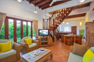 a living room with chairs and a television and a table at Traditional Thai Villa in Tropical Nature, 4BR & Pool, near Rawai Beach in Nai Harn Beach