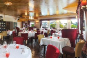 una sala da pranzo con tavoli bianchi e sedie rosse di Logis Hôtel-Restaurant Les Voyageurs a La Coquille