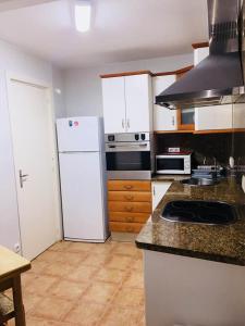 a kitchen with a white refrigerator and a stove at Vedruna Imperial Tarraco in Tarragona