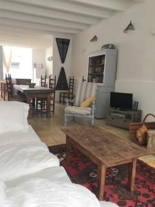ein Wohnzimmer mit einem Sofa, einem Tisch und einem TV in der Unterkunft Cosy Medieval Village House Monségur in Monségur