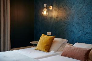 
a bedroom with a white bed and a blue wall at Hotel de France Restaurant Tast'vin in Beaune
