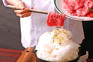 a person is holding a plate of food with meat at Okuno Hosomichi in Kobe