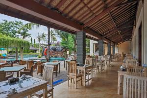 a restaurant with tables and chairs and a pool at Vila Ombak in Gili Trawangan