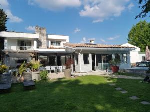 a white house with a yard with chairs and a house at Maison Lucilda in Pessac