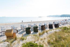 szereg krzeseł i stołów na plaży w obiekcie Hotel Meerzeit Binz w mieście Binz