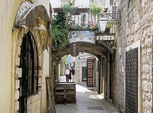 an alley with an archway in a building with plants at Altstadt von Budva in Budva